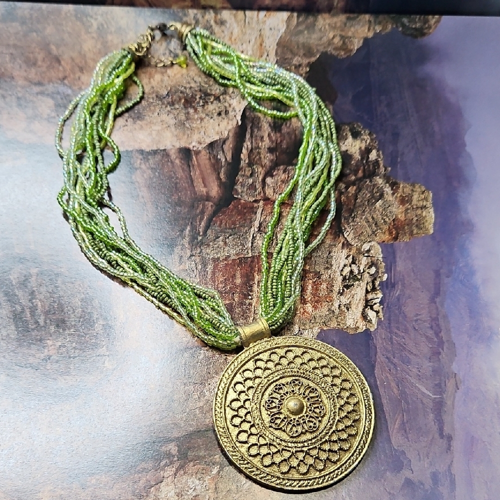 Tribal style necklace gold tone, green beaded strands with Metal Pendant